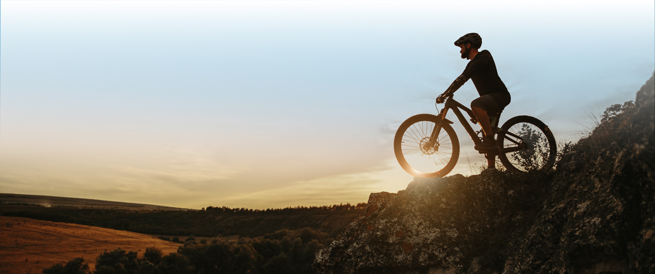 Mountainbiker auf Hügel, Abendstimmung, Blick ins Tal